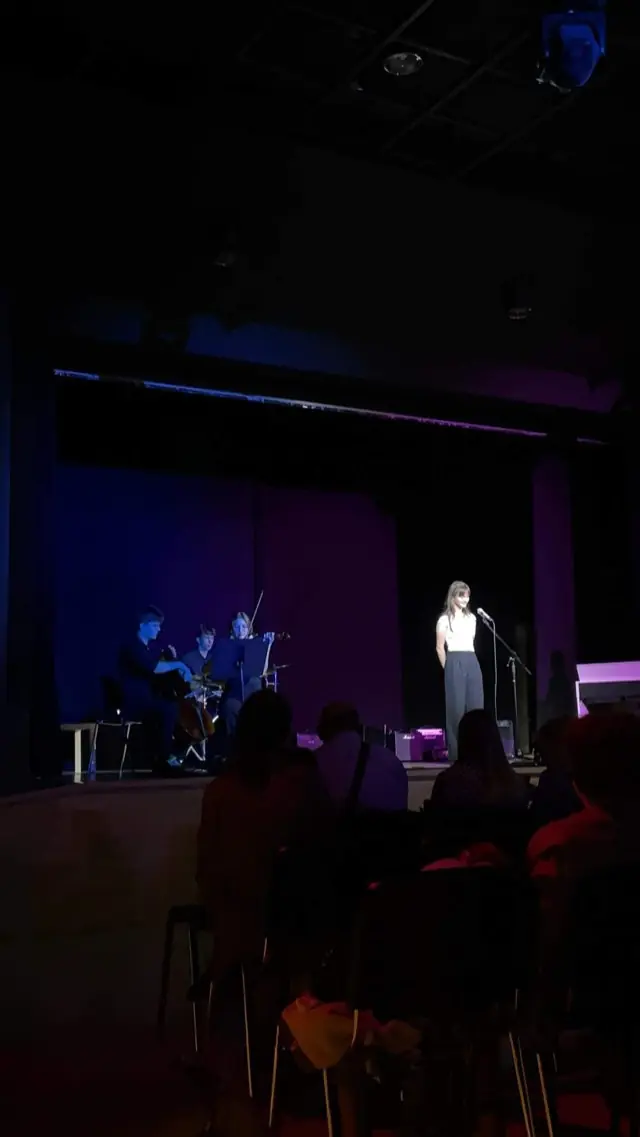 Solistka przy mikrofonie na scenie auli, pierwsza edycja koncertu w 2024 roku