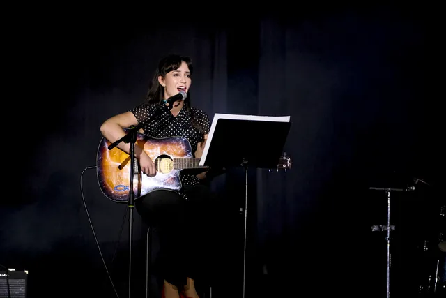 Wokalistka z gitarą akustyczną przy pulpicie z nutami